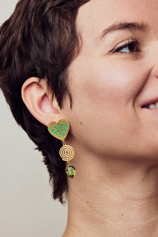 image of large firework heart earrings in green and gold on model close up smiling