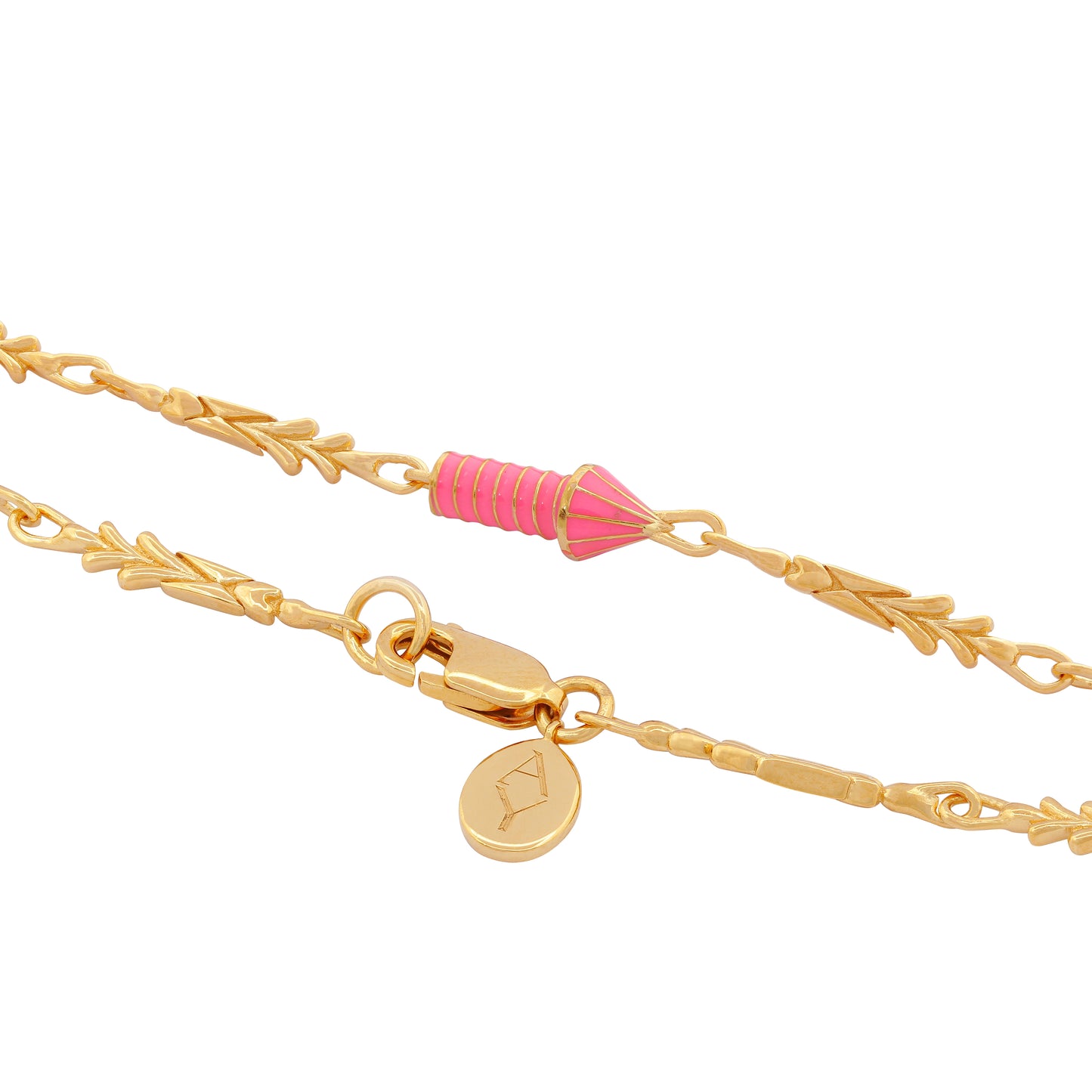 image of gold charm bracelet with pink enamel rocket close up on rocket charm and lock and logo tag on white background