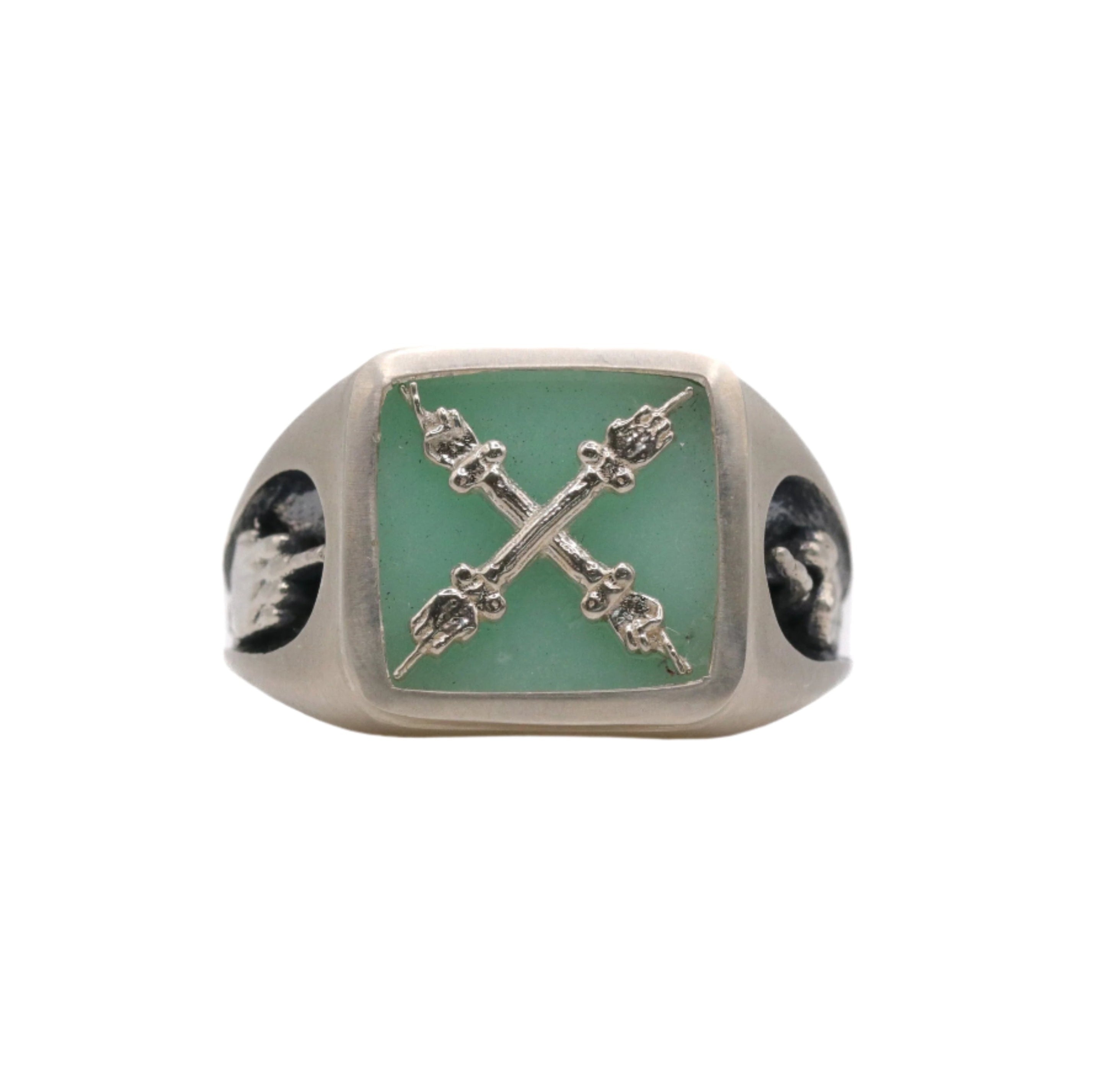 A signet ring with a square chrysoprase stone and an emblem depicting two hands on columns, with one hand's fingers crossed and the other bearing their middle finger.