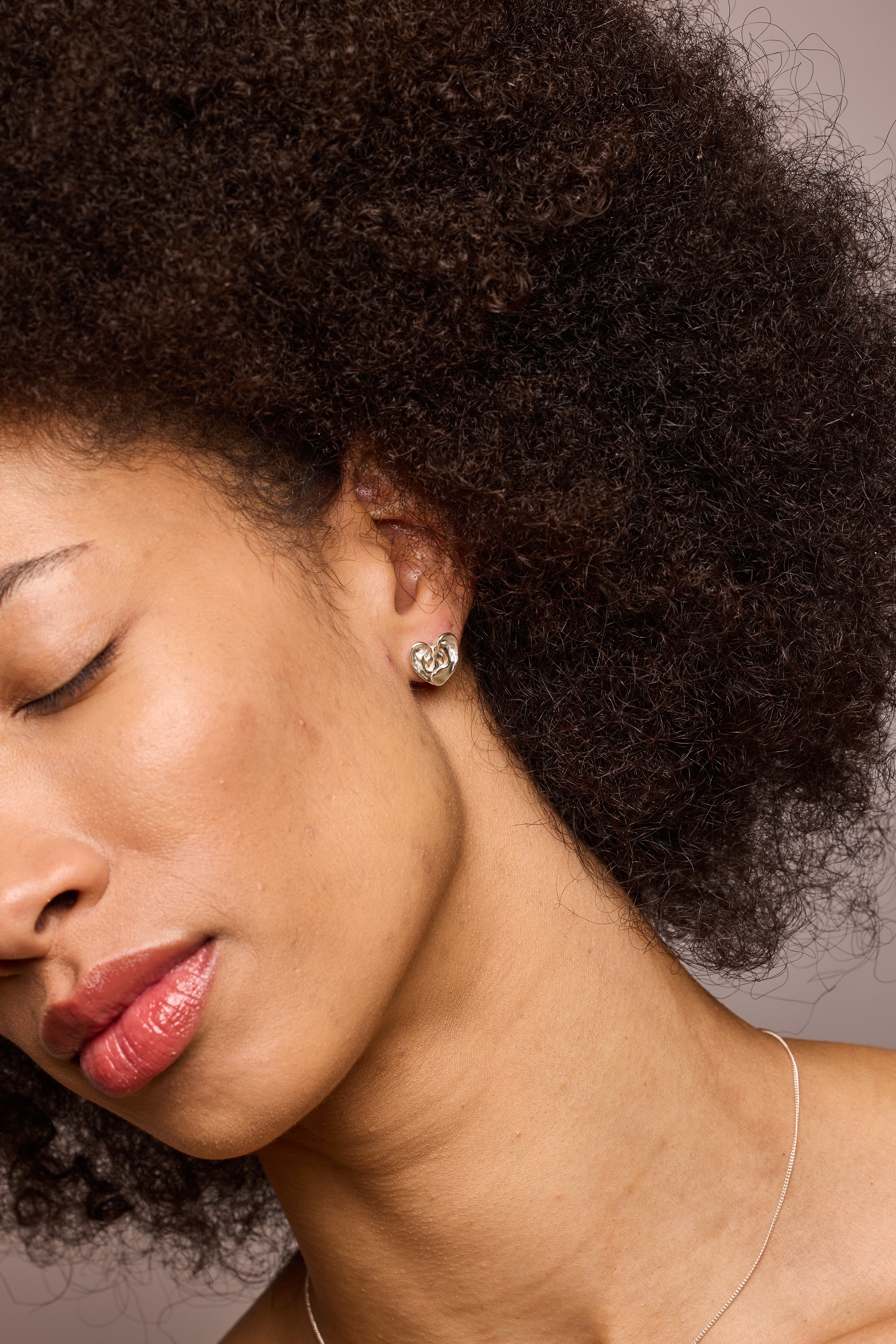 Good Listener small heart earrings shown on model with eyes closed