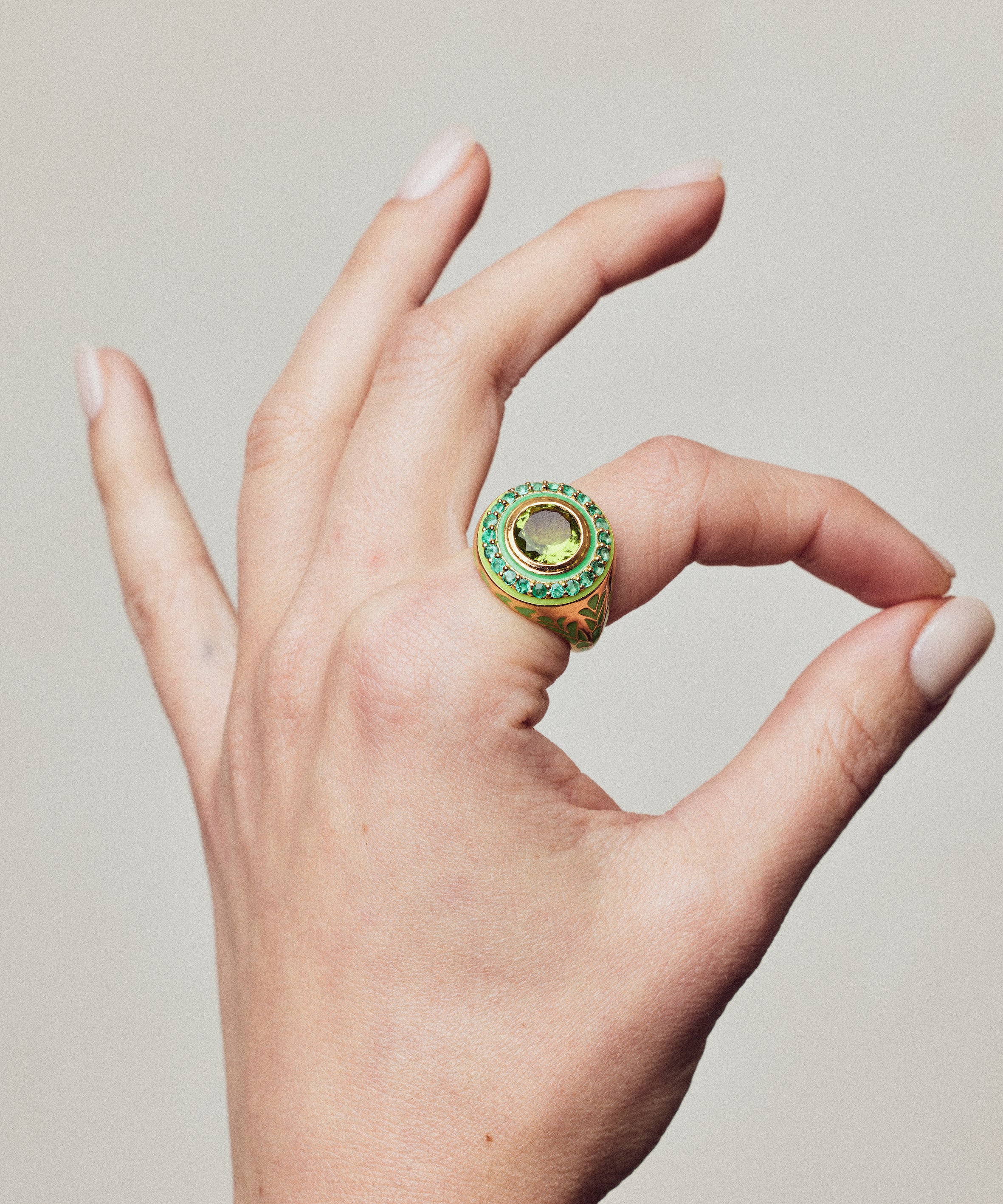 image of firework statement ring in green and gold on a hand with thumb and forefinger making circle