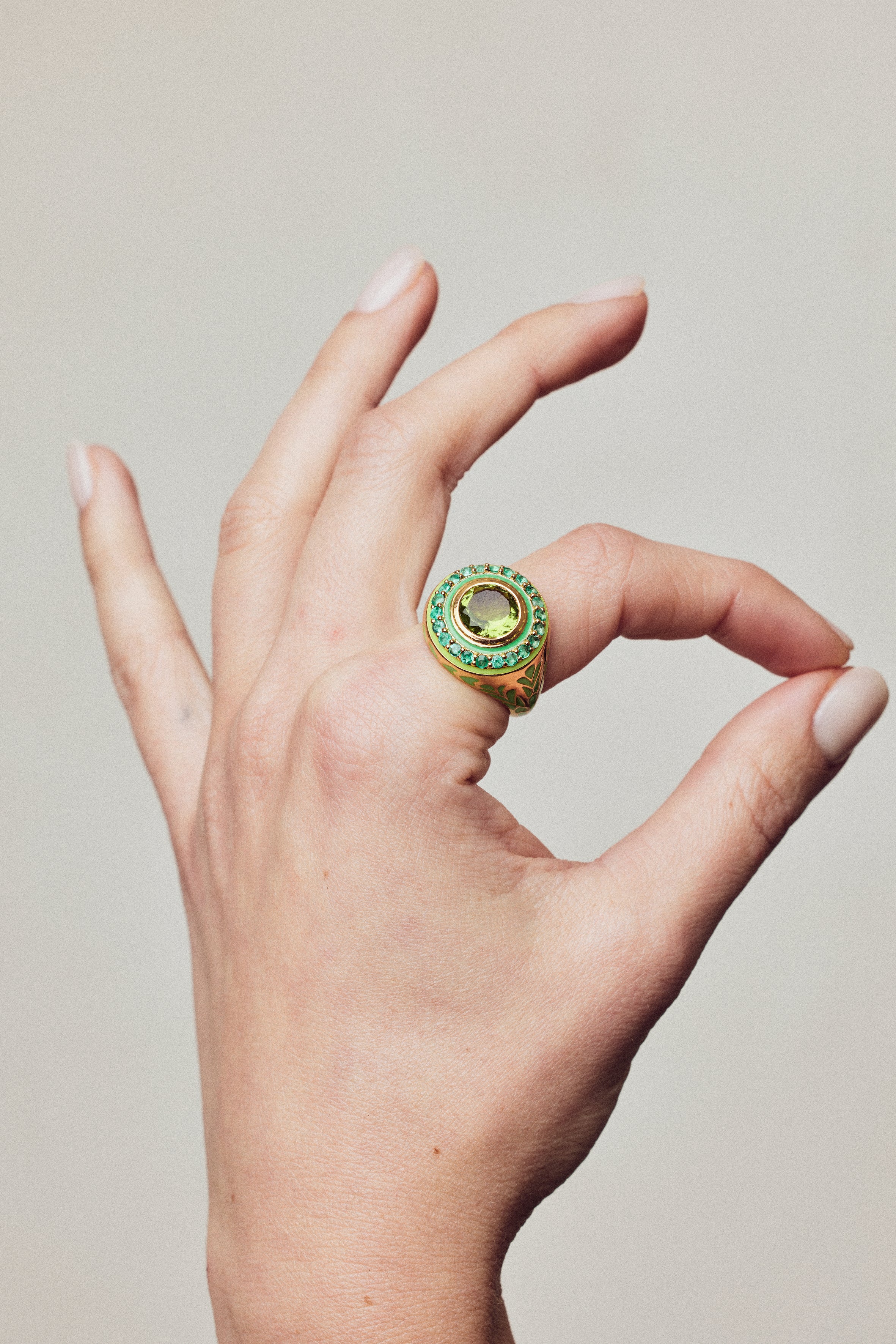 image of firework statement ring in green and gold on a hand with thumb and forefinger making circle