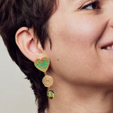 image of large firework heart earrings in green and gold on model close up smiling
