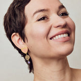 image of firework heart earrings in pink, purple and gold on model headshot smiling