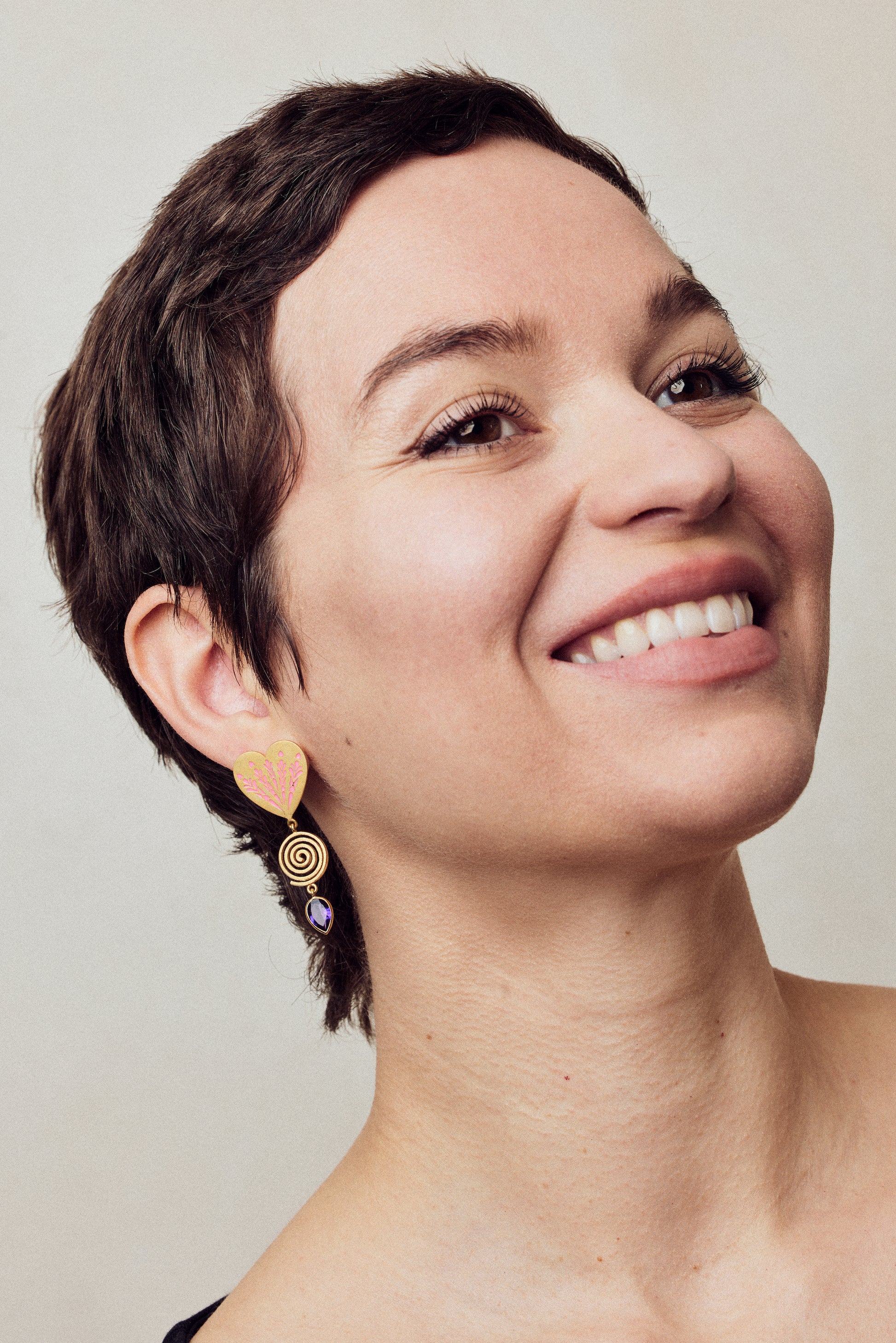 image of firework heart earrings in pink, purple and gold on model headshot smiling