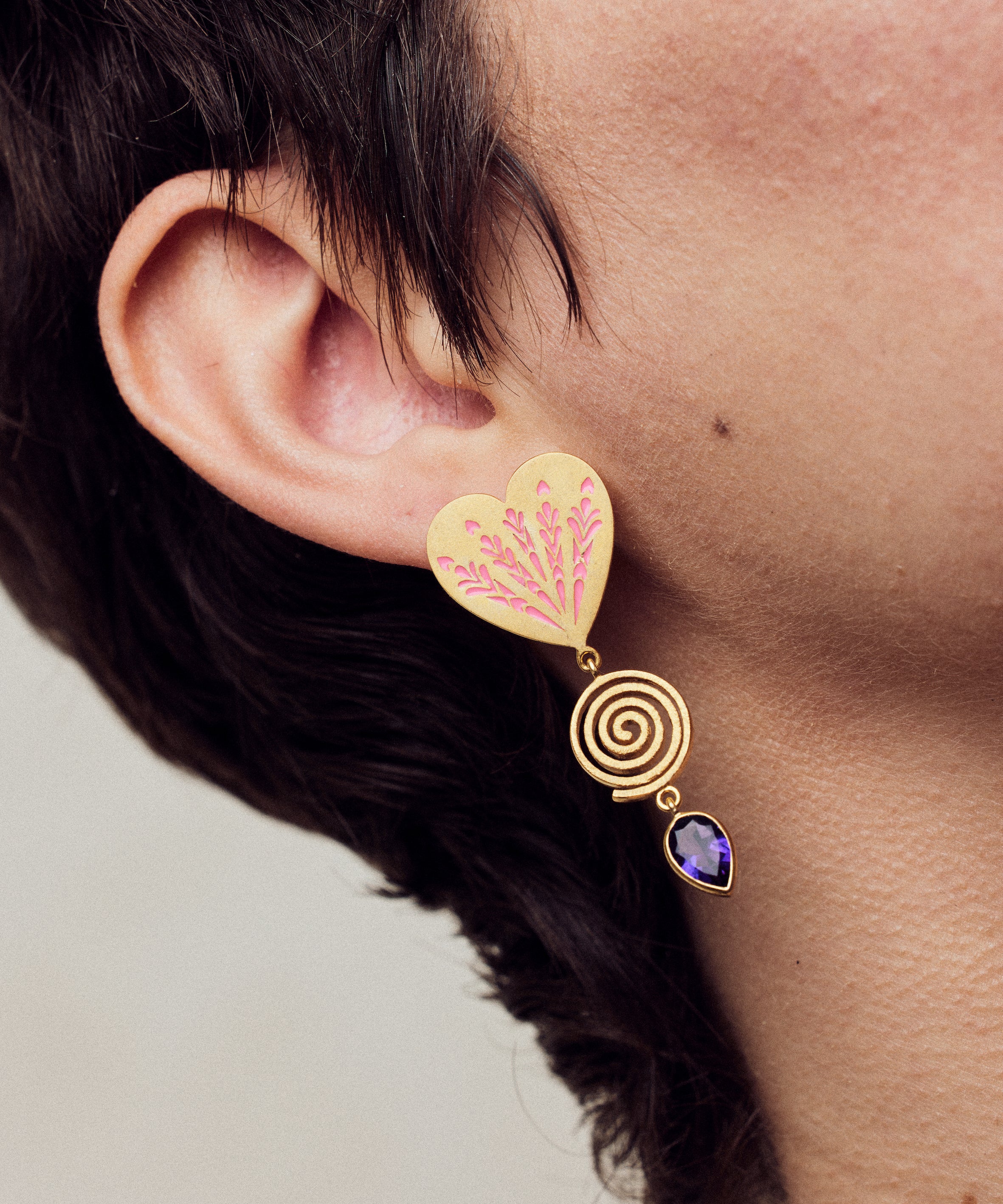 image of firework heart earrings in pink, purple and gold close up on model ear lobe