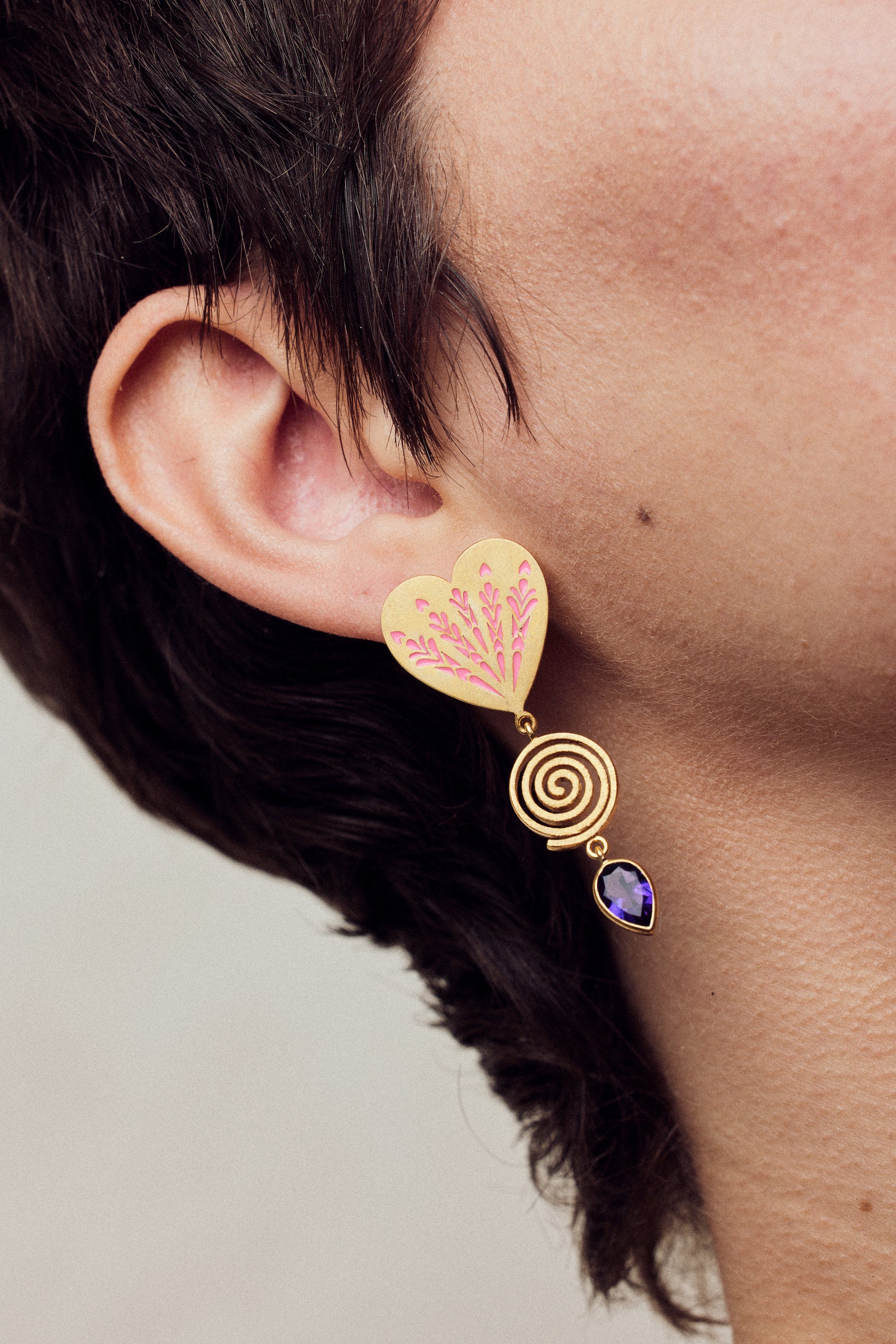 image of firework heart earrings in pink, purple and gold close up on model ear lobe