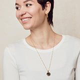  image of sparkler diamond initial necklace, letter C on long chain, on model in white long-sleeved top with short brown hair smiling