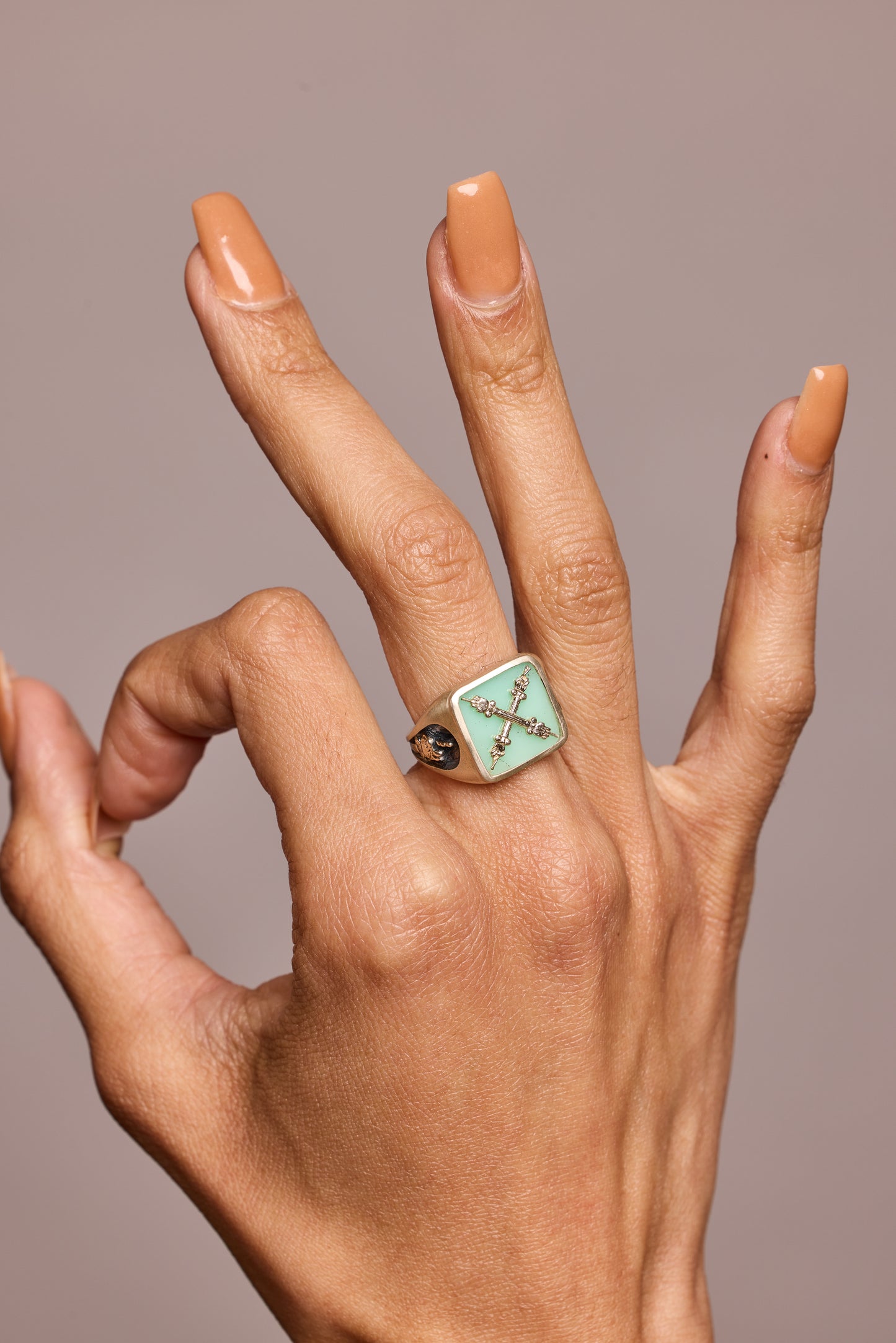 A signet ring with semi-precious stone chrysoprase worn on a hand giving the A okay sign