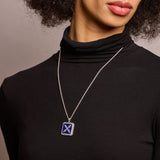 Introvert crest necklace in lapis and sapphire on long silver chain on model in black turtleneck top