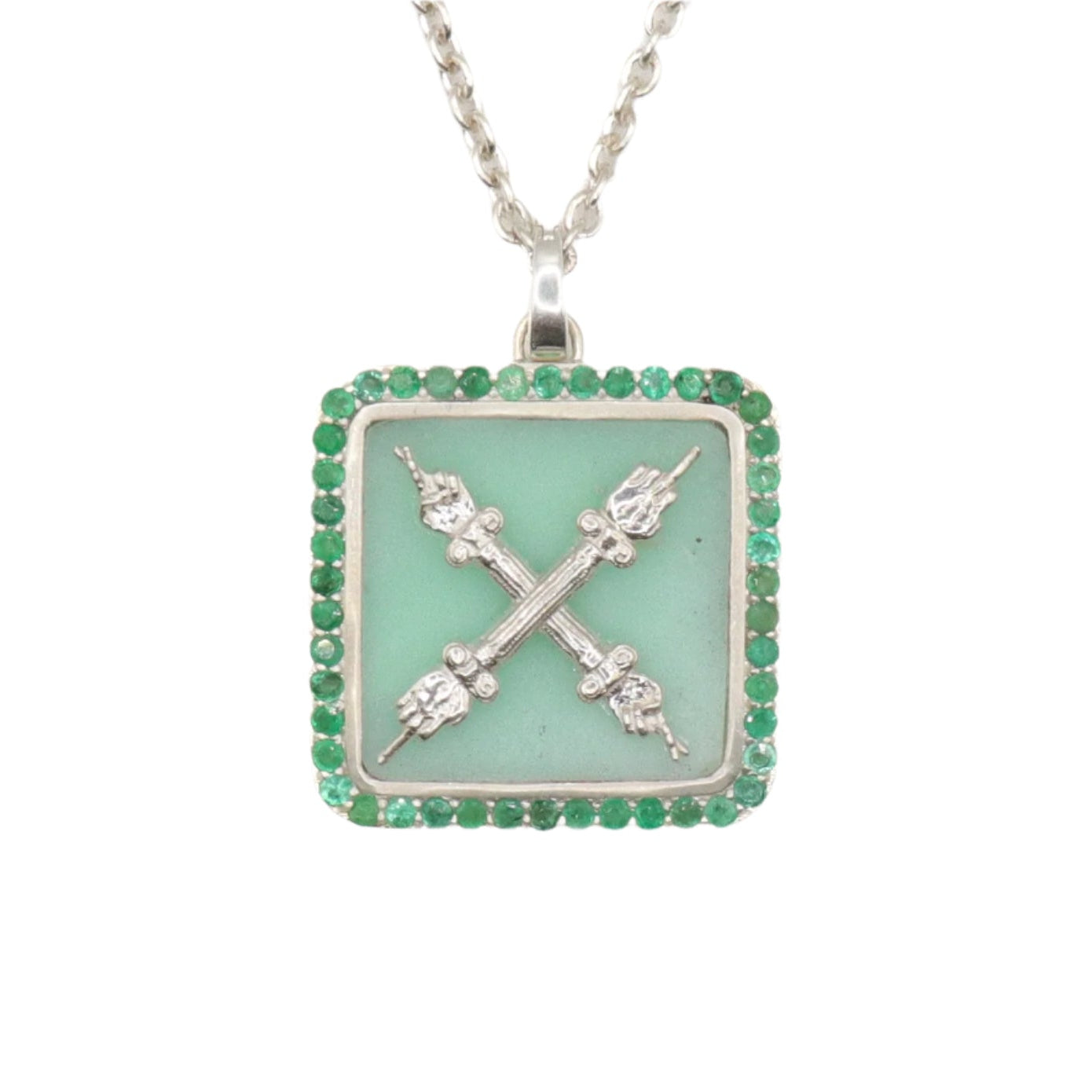 A square-shaped necklace pendant with a crest motif design, featuring chrysoprase and natural emeralds, set in recycled sterling silver, displayed on a chain.
