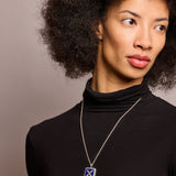 Introvert crest necklace in sapphire and lapis on long silver chain on model in black top