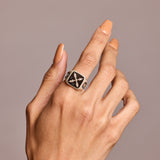 Signet ring in semi-precious stone black onyx shown on hand against grey background