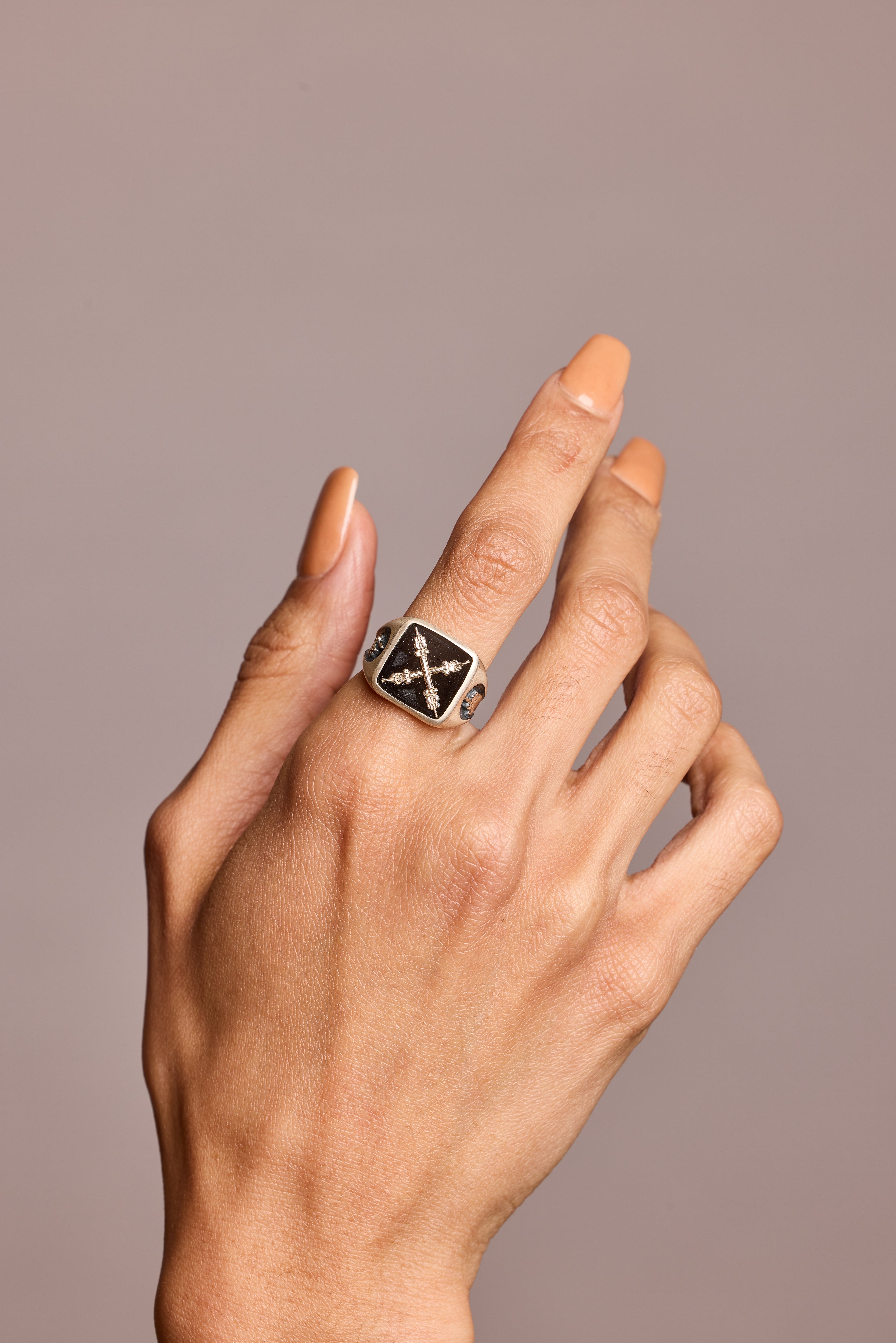 Signet ring in semi-precious stone black onyx shown on hand against grey background