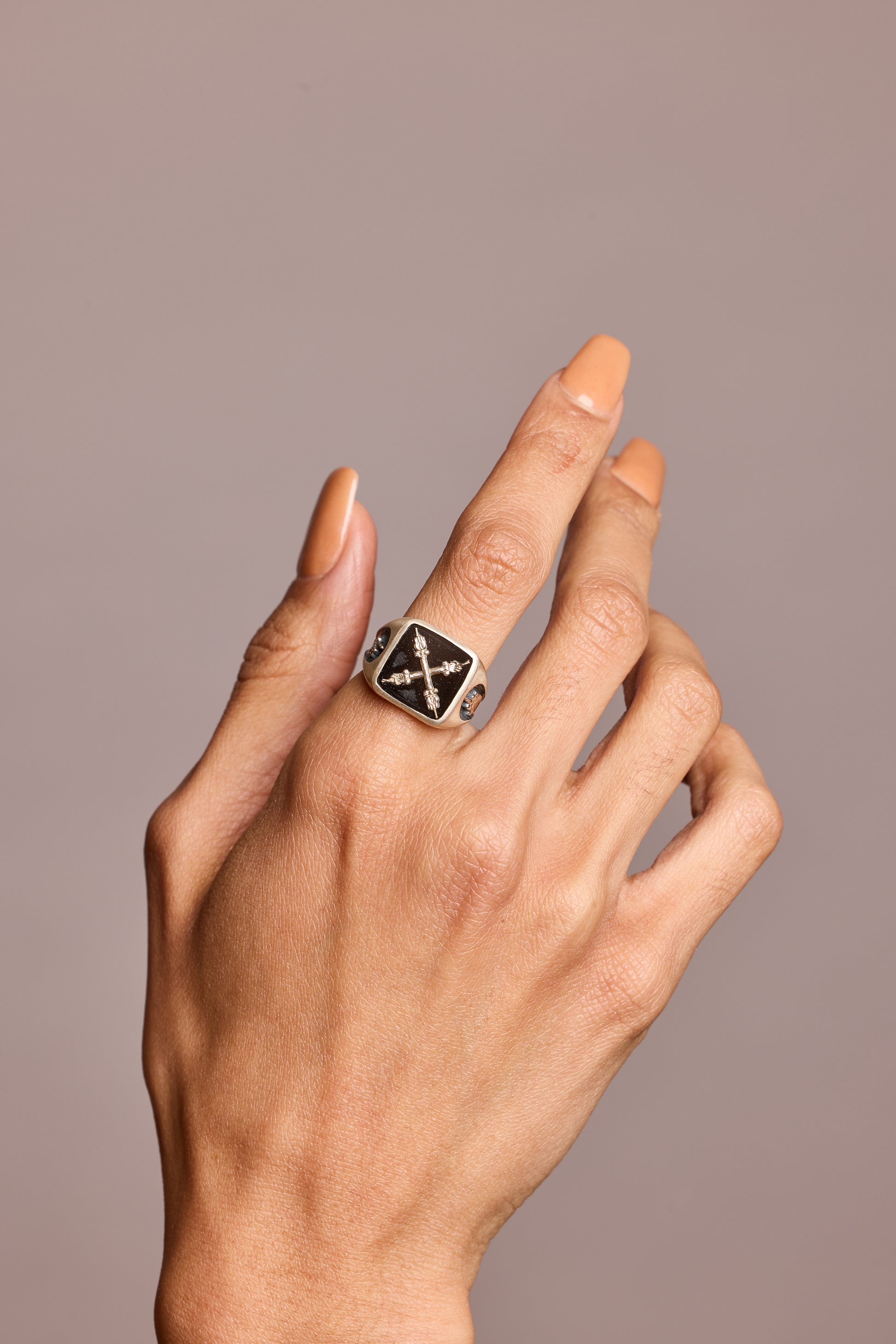 Signet ring in semi-precious stone black onyx shown on hand against grey background