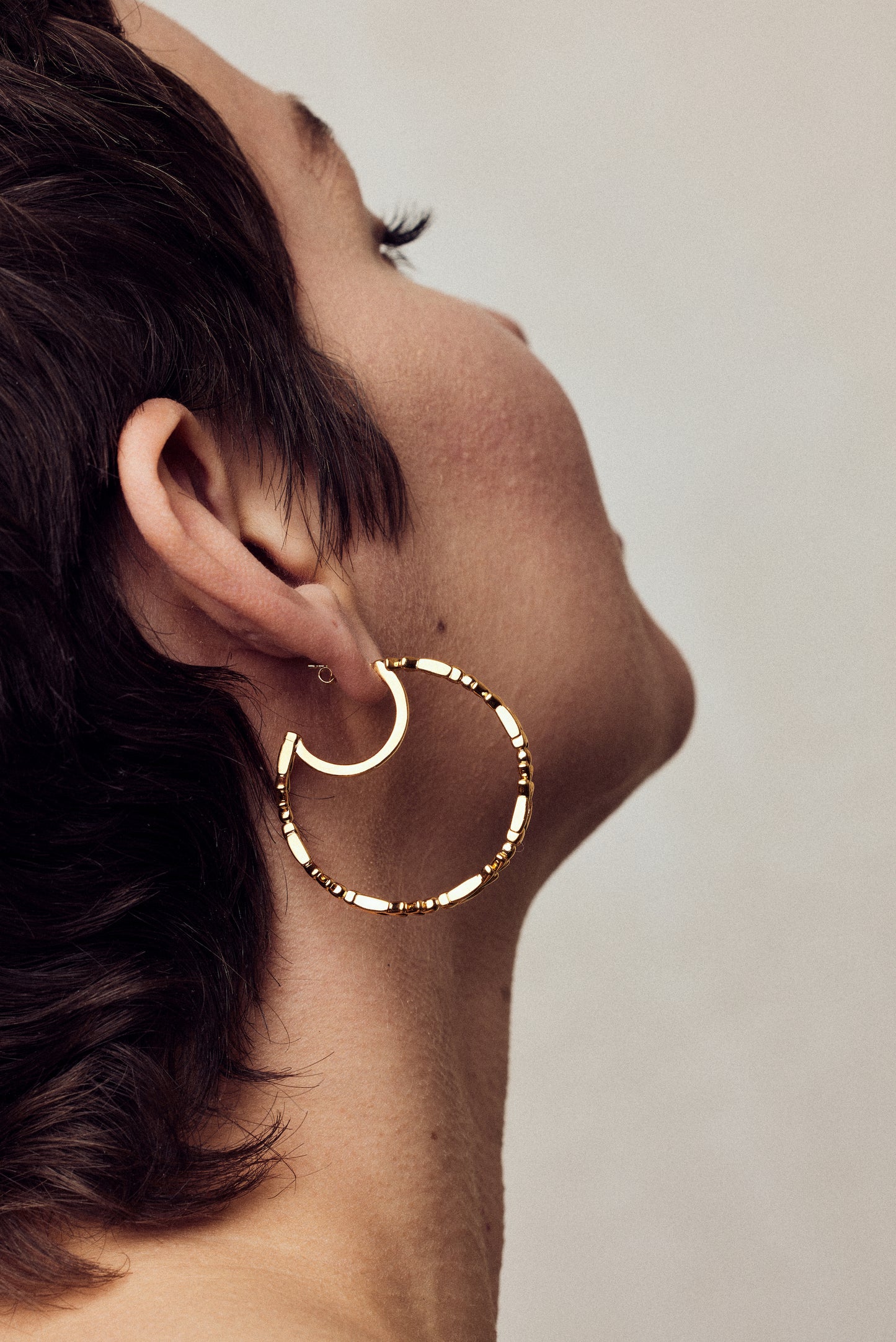 image of large firework gold hoop earrings on model shot from behind showing earring full side view