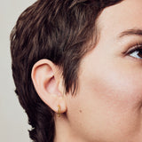 image of firework gold mini hoops on model with short brown hair facing right