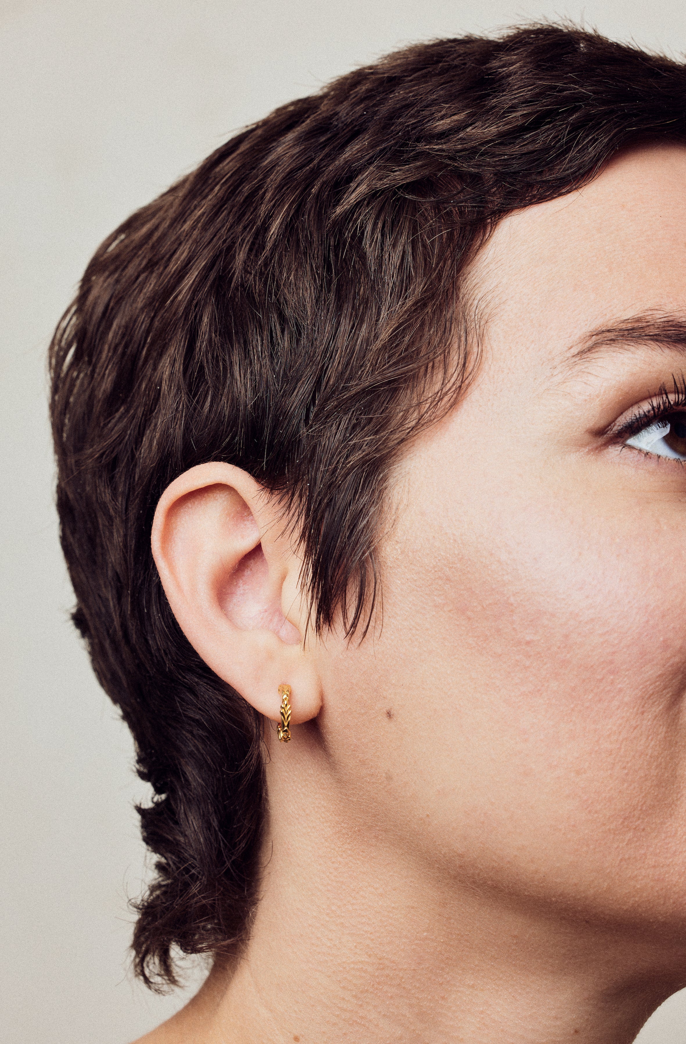 image of firework gold mini hoops on model with short brown hair facing right