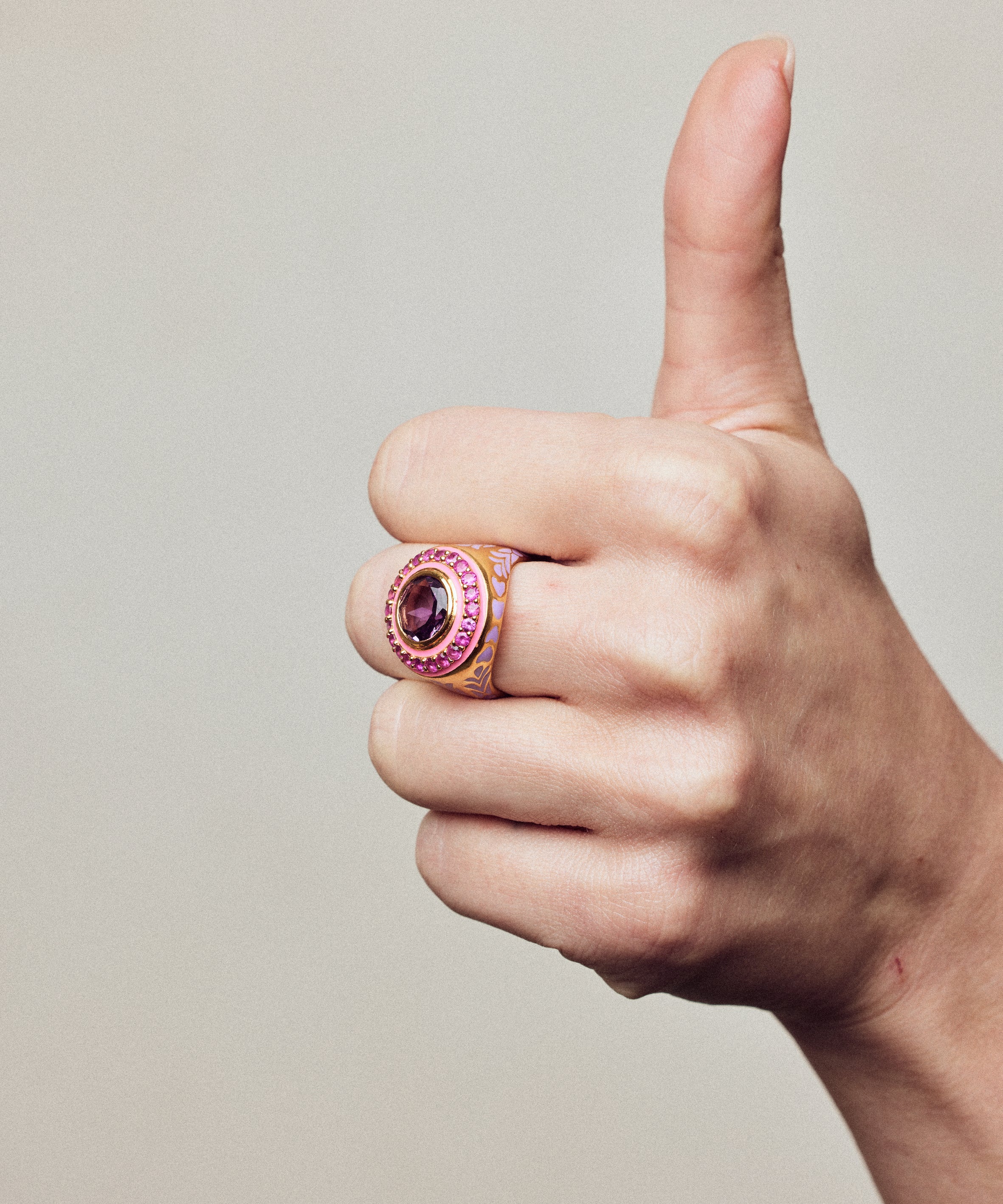 Image of statement firework ring in pink, purple and gold. On hand making thumbs up.