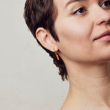 image of rocket enamel earrings in orange and gold shown on model with white skin and short brown hair