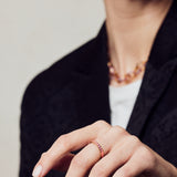 image of spark enamel ring in pink and gold on hand in forefront of image on model in black jacket