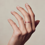 image of spark enamel ring in pink and gold on hand with fingers stretched upwards against beige background