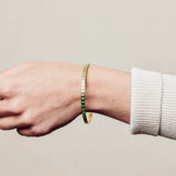 image of spark enamel bangle on wrist of woman with white skin wearing cream ribbed top