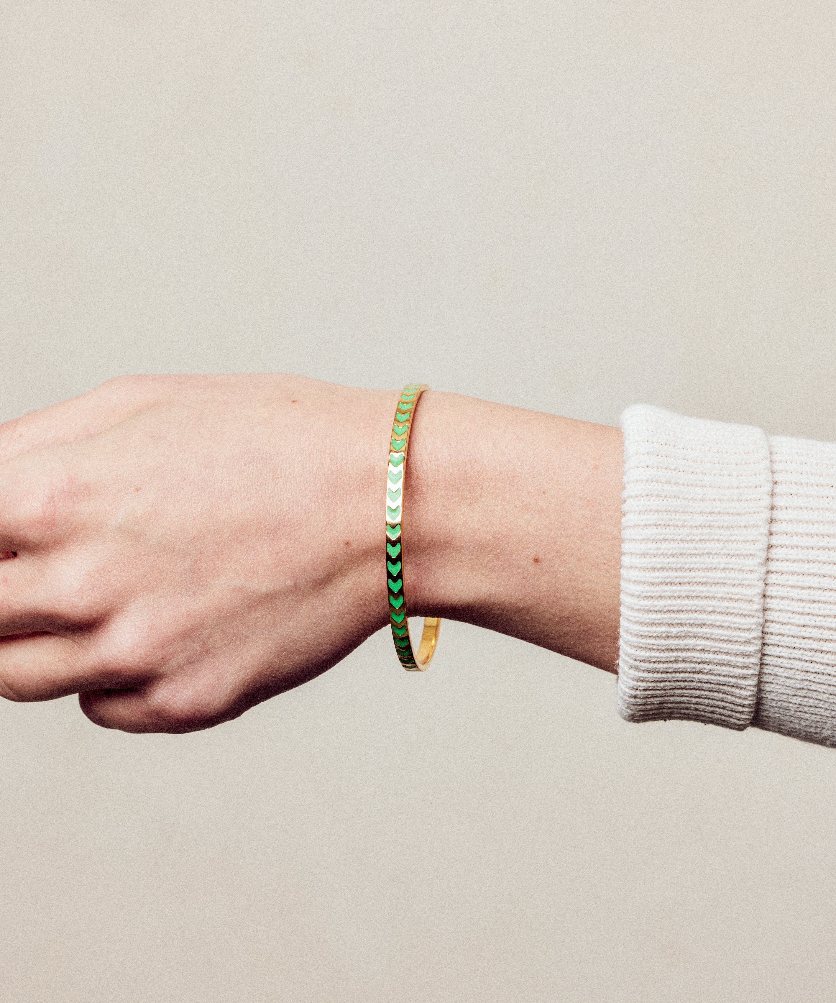 image of spark enamel bangle on wrist of woman with white skin wearing cream ribbed top