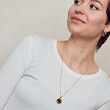  image of sparkler diamond initial necklace, letter C on long chain, on model in white top with short brown hair looking off to the left