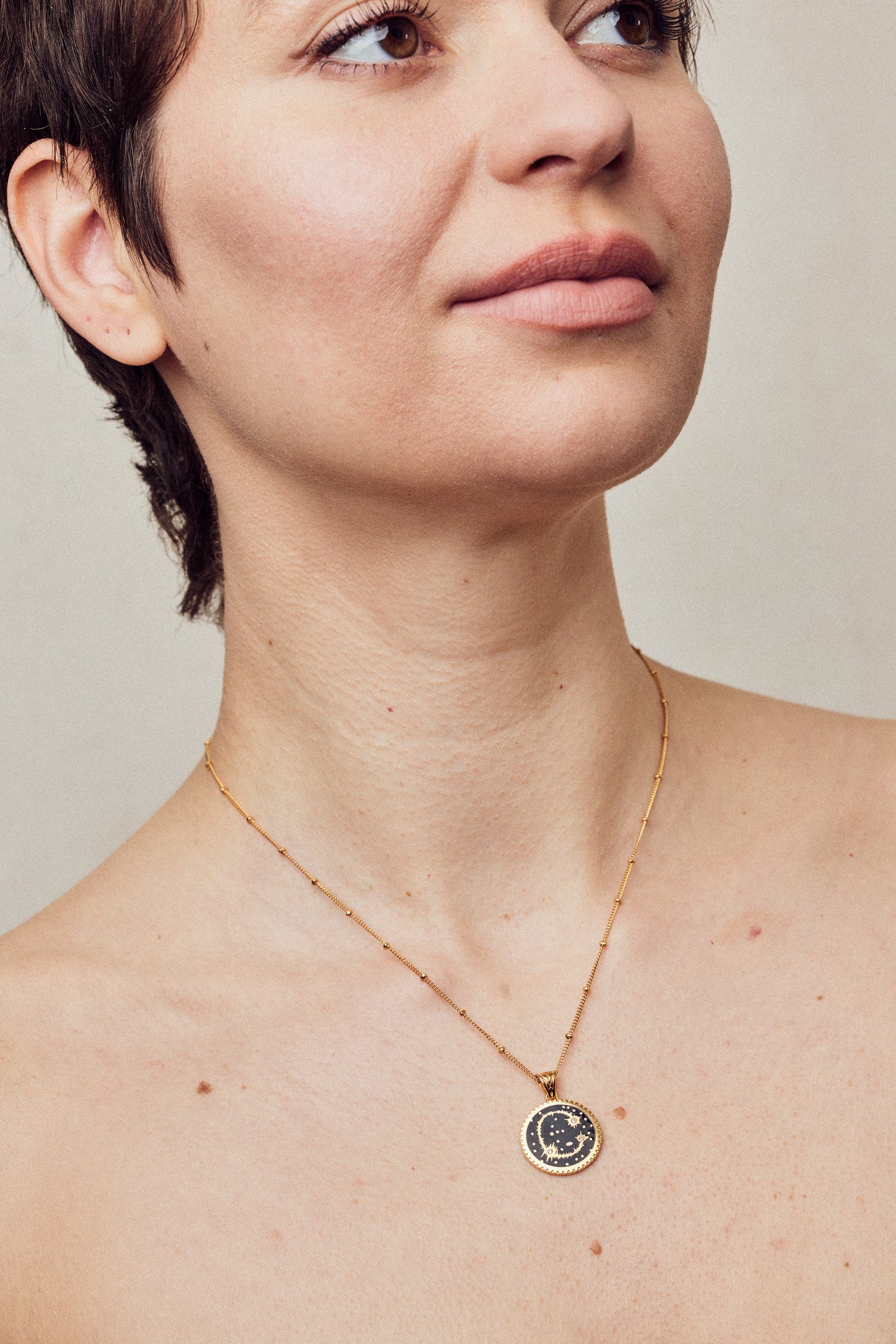 image of diamond initial necklace on short chain shown on bare chest of woman with short brown hair