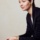 image of spark enamel bangle in green and gold on model with short brown hair seated with arms resting on lap