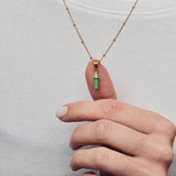 image of rocket enamel necklace on model showing close up of hand holding pendant with thumb