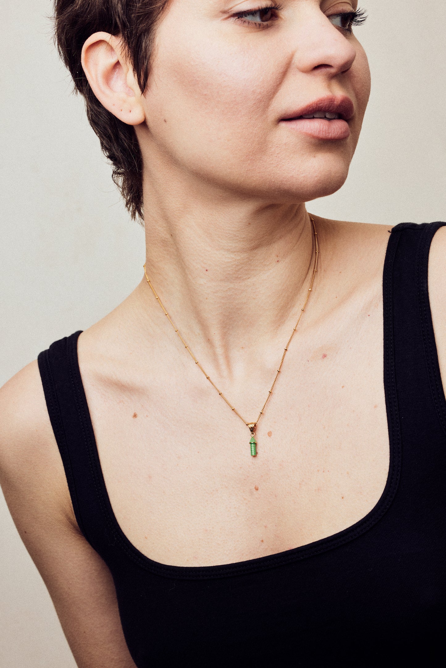 image of rocket enamel necklace on model with short brown hair facing right wearing black tank top