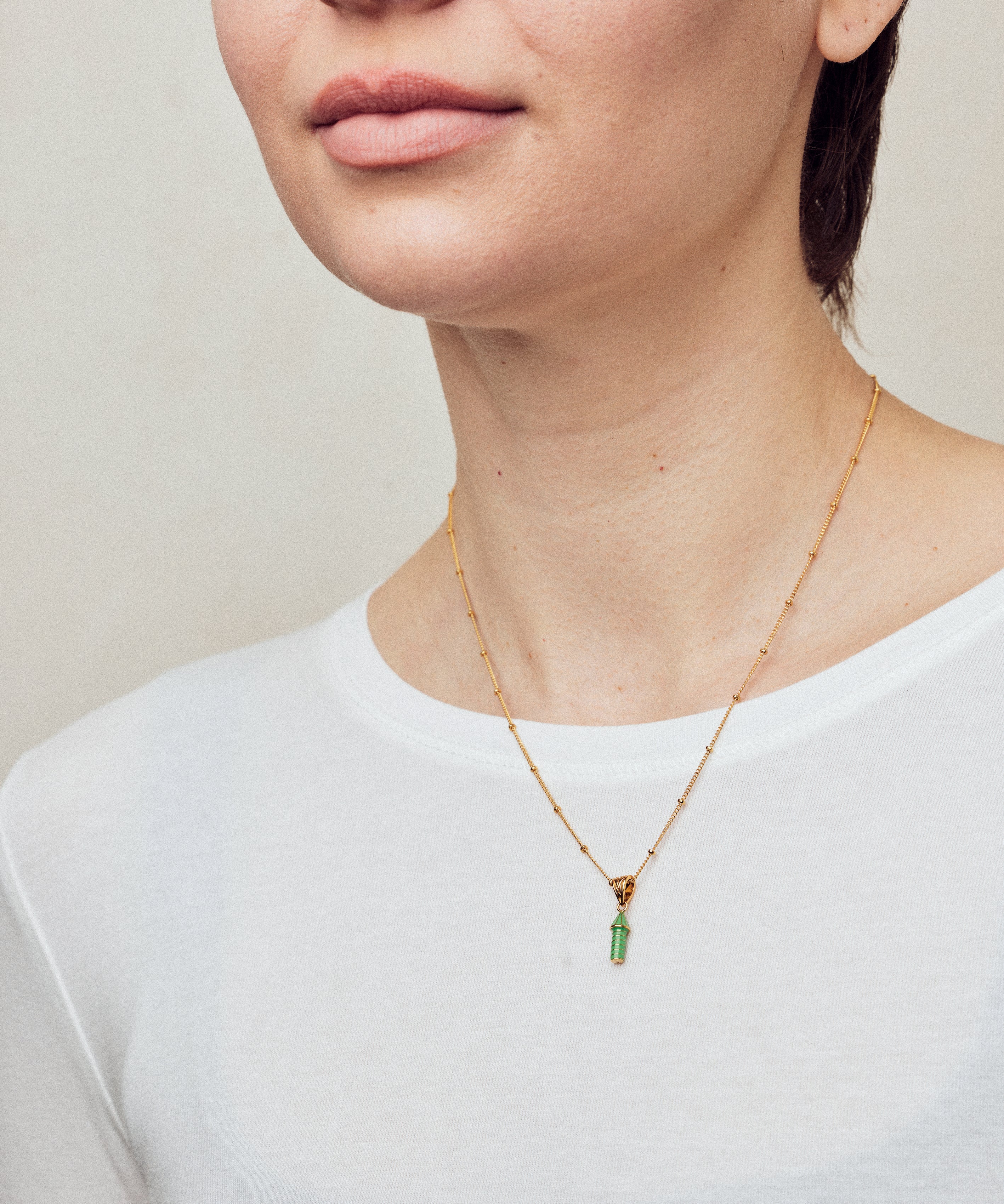 image of rocket enamel necklace on model with short brown hair wearing white top