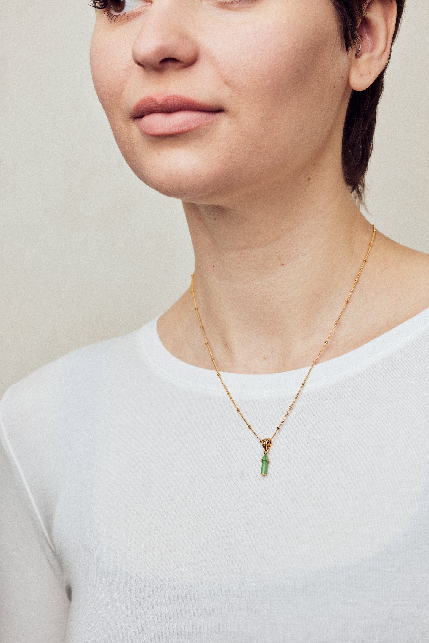 image of rocket enamel necklace on model with short brown hair wearing white top