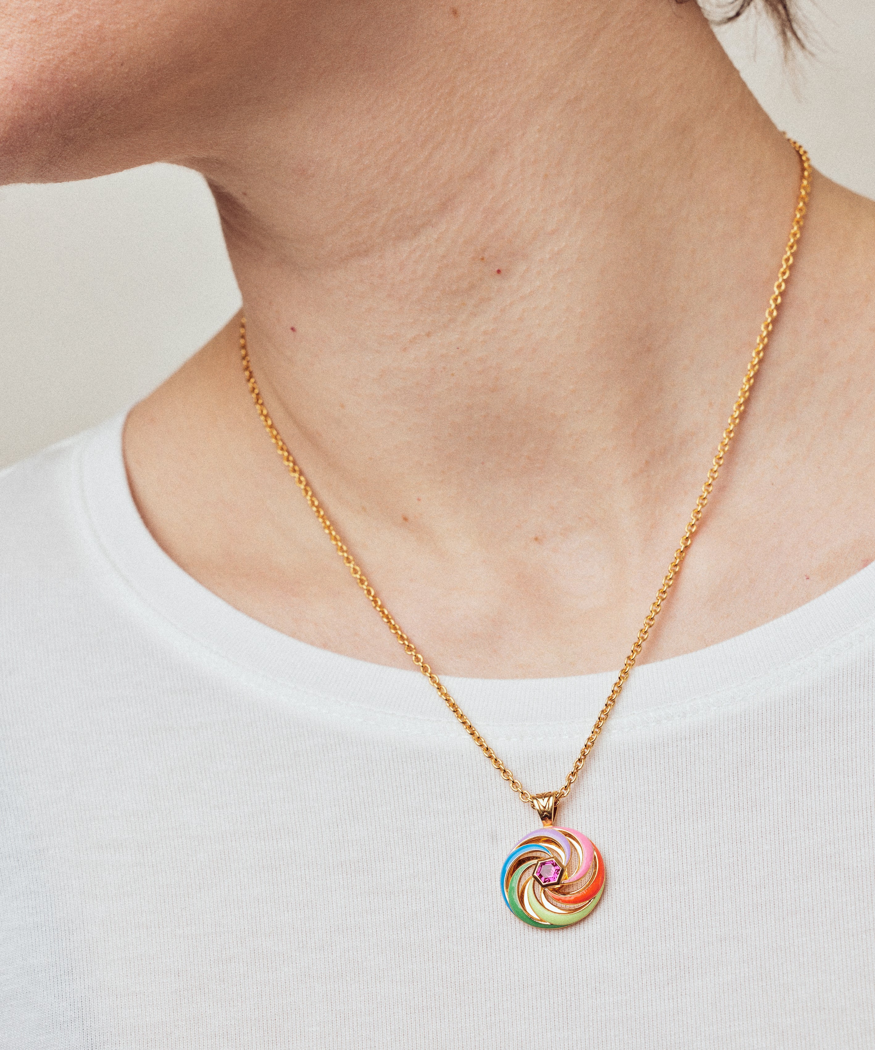 image of enamel necklace with spinning disk on short chain on model in white top close up on neck