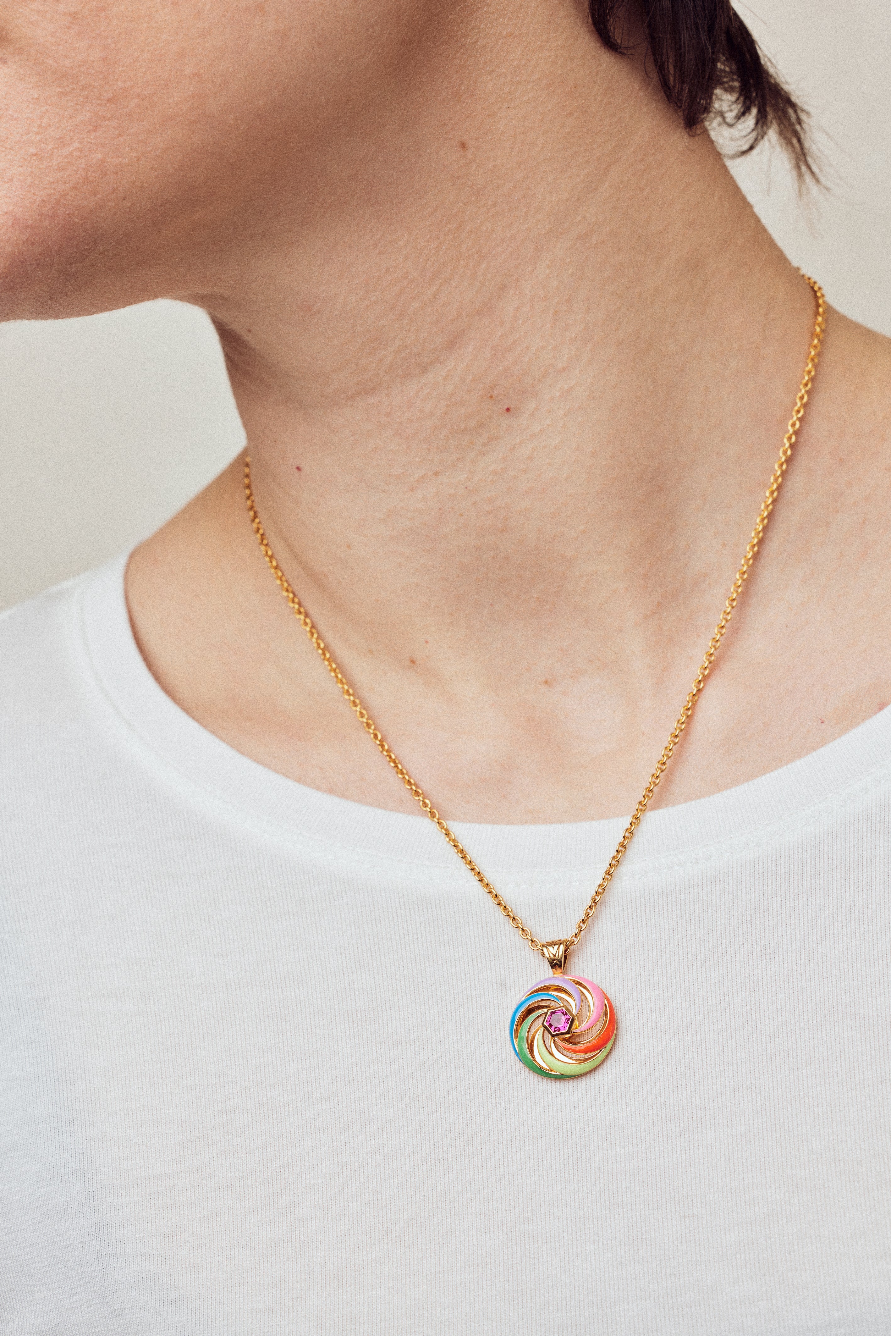 image of enamel necklace with spinning disk on short chain on model in white top close up on neck