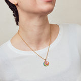 Image of enamel necklace with spinning disk on short chain on model in white top smiling