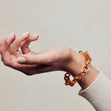 image of spark gold chain bracelet in orange and gold shown on wrist with palm facing upwards and fingers curled