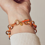 image of gold chain bracelet in orange of gold on wrist with arm outstretched in cream ribbed top