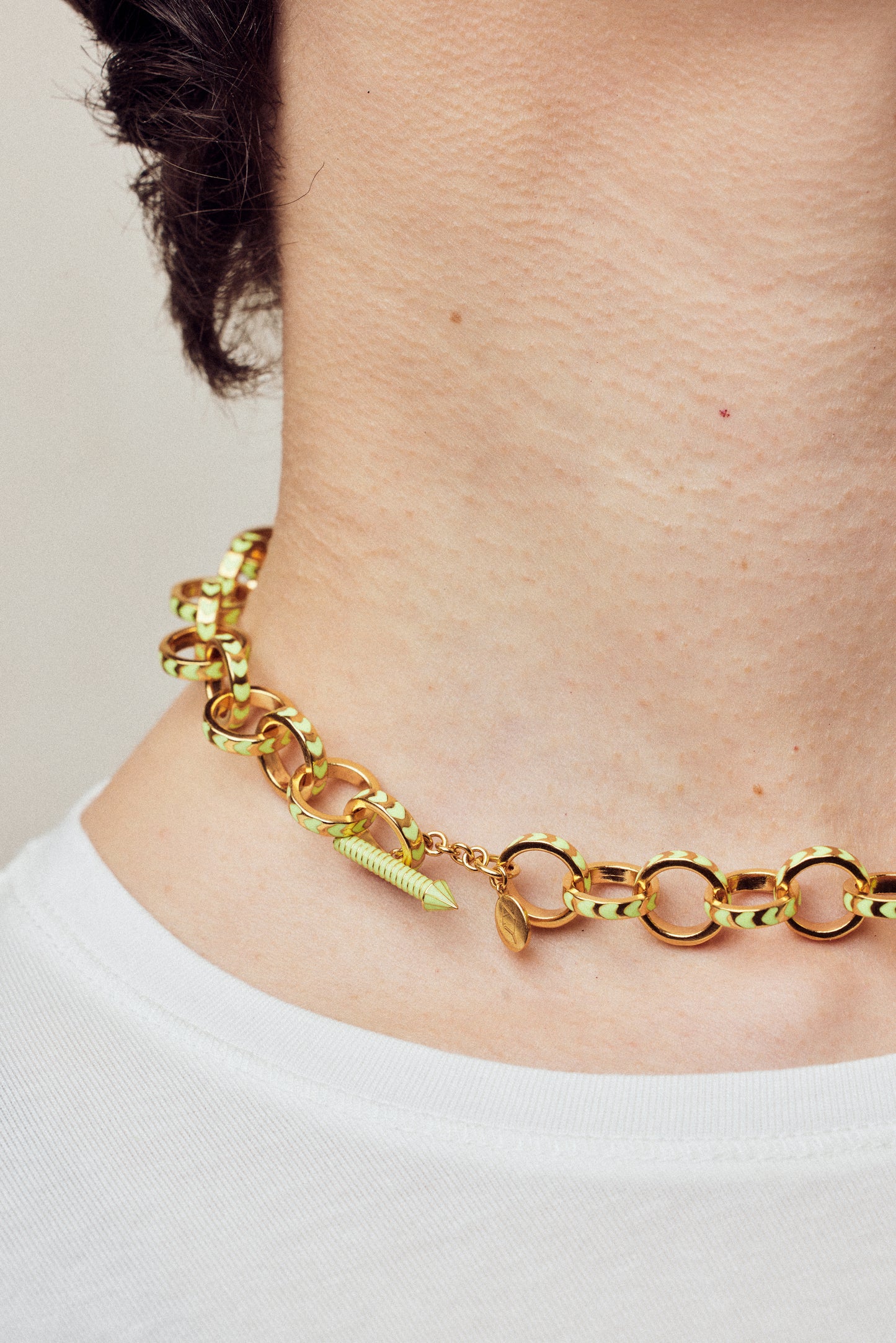 image of spark gold chain necklace in neon yellow and gold shown close up on neck of model with white skin and short brown hair