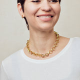image of spark gold chain necklace shown on model with short brown hair wearing white round neck top and smiling