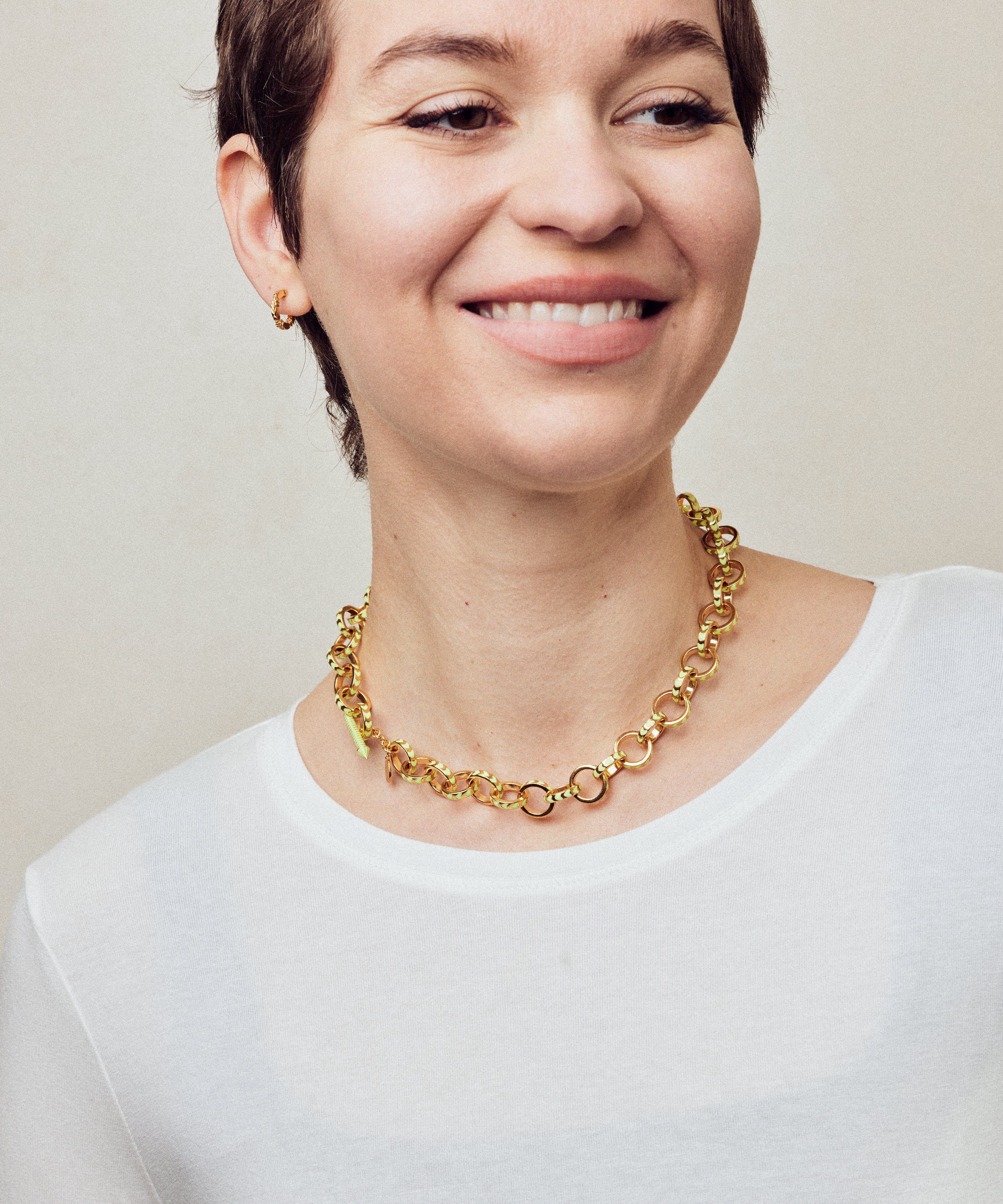image of spark gold chain necklace shown on model with short brown hair wearing white round neck top and smiling