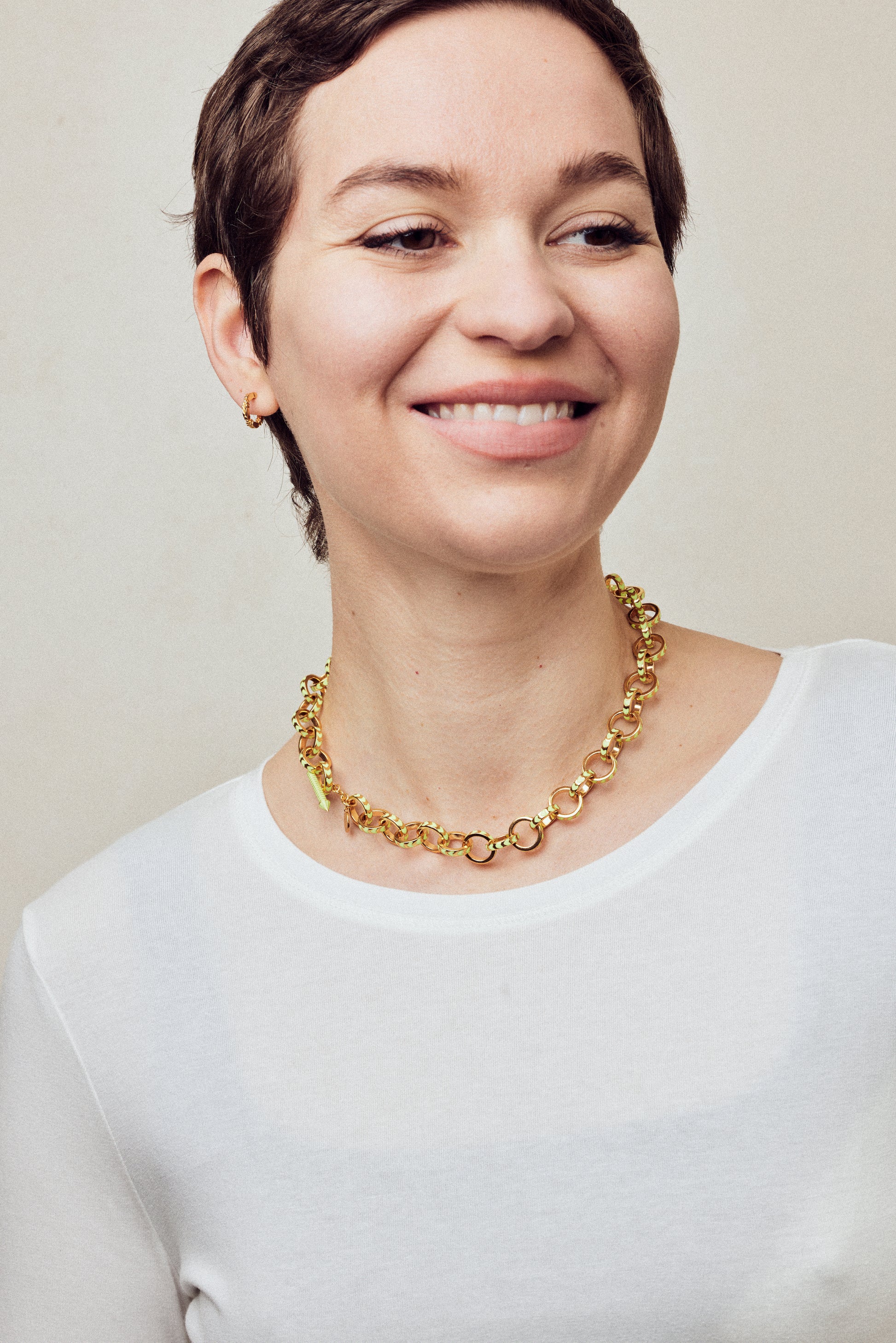 image of spark gold chain necklace shown on model with short brown hair wearing white round neck top and smiling