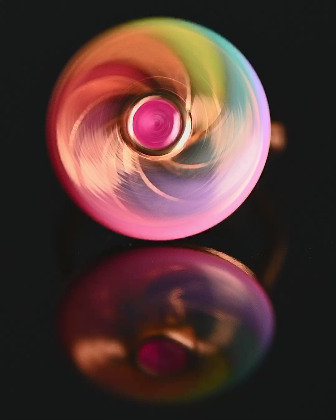 video of spinning ring with mulit-coloured enamel and ruby hex centre spinning on black background with music 